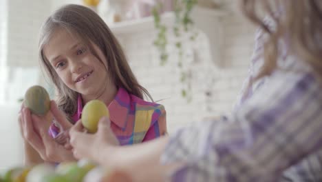 Woman-hand-holding-Easter-egg-while-concentrated-little-girl-painting-on-it