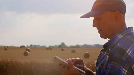 Agricultura-moderna.-Amor-a-la-agricultura.-Granjero-usando-la-tableta-digital-mientras-examina-la-granja