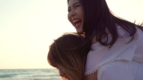 Jóvenes-amigos-LGBT-asiáticos-jugando-en-la-playa,-hermosas-mujeres-amigas-se-sienten-felices-y-divertidas-relajarse-jugando-en-la-playa-cerca-del-atardecer-en-el-mar-en-la-noche.-Lifestyle-amistad-lesbiana-viaje-en-la-playa.-Disparo-a-cámara-lenta.