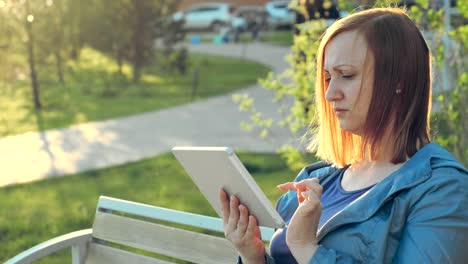 Frau-mit-Tablet-Computer-sitzt-auf-Bank-in-der-Stadt