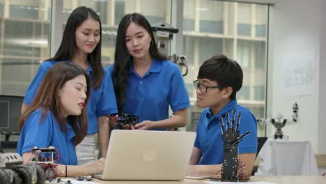 Young-asian-creative-engineers-meeting,-programming-for-collaborative-universal-robotics-at-laptop-in-workshop.-People-with-technology-or-innovation-concept.