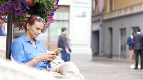 Young-woman-sitting-in-the-street-cafe-at-the-terrace-and-using-her-smartphone.