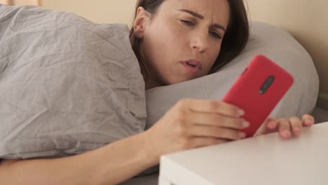 Woman-waking-up-and-using-mobile-phone-in-bed