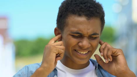 Adolescente-niño-cerrando-los-oídos-del-dolor,-sufriendo-zumbido,-daño-auditivo