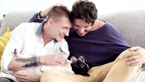 Gay-couple-relaxing-on-couch-with-dog.-Playing-with-a-dog.