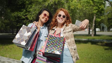 Hübsche-Mädchen-machen-Selfie-mit-Smartphone-hält-Einkaufstaschen-im-Stadtpark