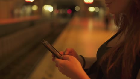 Close-up-Attractive-redhead-woman-with-freckles,-piercings-and-red-hair-chatting-on-smartphone-at-metro-subway-station,-during-sunny-summer-in-Paris.-Blurred-underground-background.-4K-UHD.