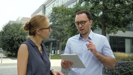 Business-people-talking-outside-with-electronic-tablet