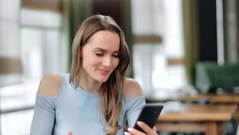 Closeup-laughing-girl-eating-food-looking-at-screen-of-smartphone.-Shot-with-RED-camera-in-4K