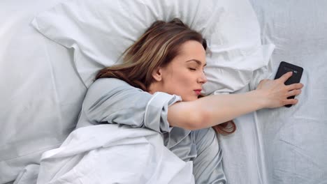 Sleeping-woman-lying-on-bed-awaking-from-mobile-call-at-morning.-Close-up-shot-on-4k-RED-camera