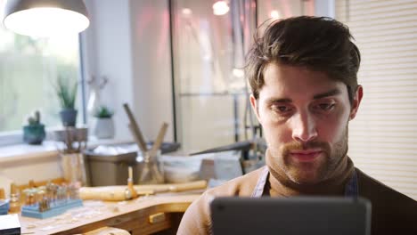 Male-Jeweller-Looking-At-Design-On-Digital-Tablet-In-Studio