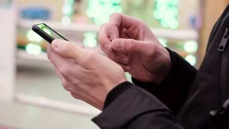 Close-up-of-young-man-hands-using-smartphone-outdoors