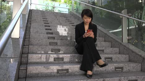 Relax-For-Asian-Businesswoman-Texting-With-Smartphone-Sitting-On-Stairs