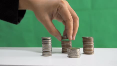 Close-up-shot-hand-of-woman-removing-stack-of-the-coins-over-green-background