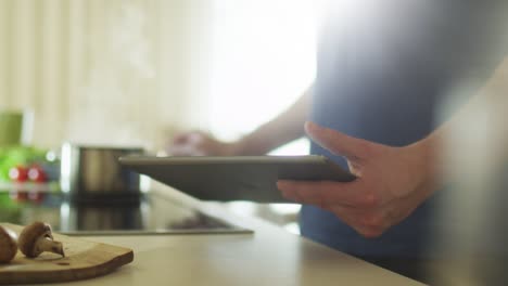 El-hombre-está-usando-Tablet-PC-mientras-prepara-alimentos