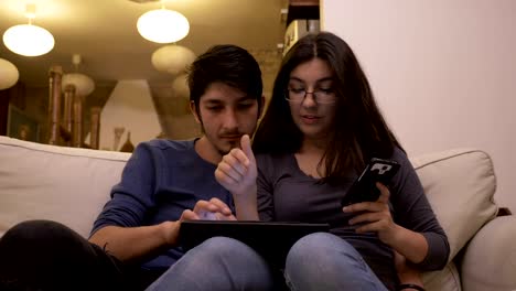 Jóvenes-en-el-hogar-del-hombre-utilizando-el-tablet-pc-y-mujer-teléfono-inteligente-compras-y-pagar-en-línea-con-bitcoin-y-cryptocurrencies