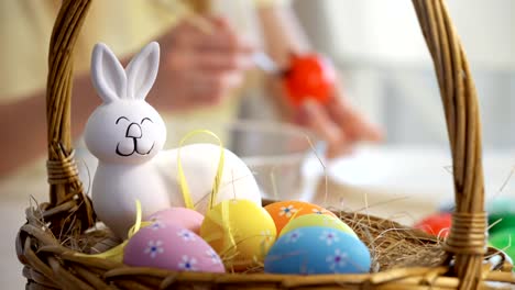 Frohe-Ostern!-Mutter-und-ihre-kleine-Tochter-tragen-lustige-Hasenohren-Ostereier-färben