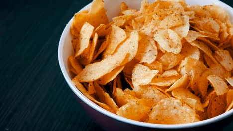 Großer-Teller-mit-Kartoffel-Chips-auf-dem-Tisch.-Weibliche-Hände-mit-schönen-Maniküre-nehmen-chips