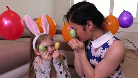 Happy-mother-and-daughter-keeping-Easter-eggs-near-eyes