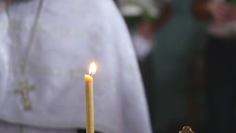 Die-Kerze-brennt-in-einer-Kirche.-Priester-in-den-Hintergrund.-selektiven-Fokus