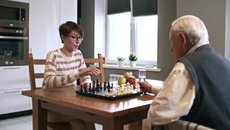 Laughing-Woman-Playing-Chess-with-Senior-Man