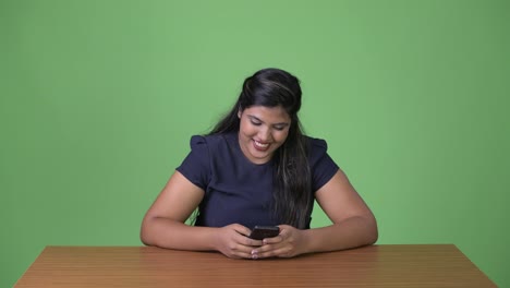 Young-overweight-beautiful-Indian-businesswoman-against-green-background