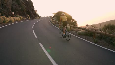 Cyclist-sitting-on-a-bike-taking-pictures-on-a-smartphone-for-social-networking-mountain-landscape-at-sunset.-Slow-motion