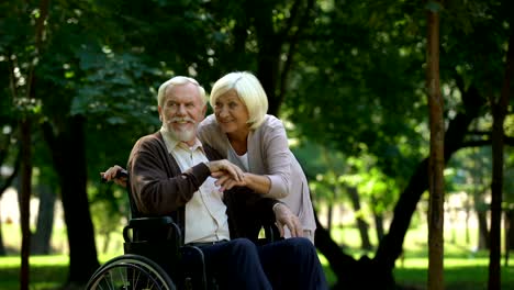 Pareja-descansando-en-el-Parque-mirando-a-sus-nietos,-hombre-sentado-en-silla-de-ruedas