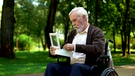 Con-discapacidad-abuelo-mirando-militar-token-en-la-caja-blanca,-Fondo-de-la-patria