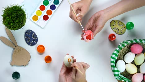 Frauen-Hände-dekorieren-Eier-auf-Tisch,-Osterbräuche,-Familienanschluss