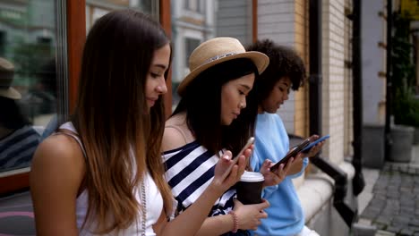 Chicas-guapas-absorto-en-sus-teléfonos-al-aire-libre