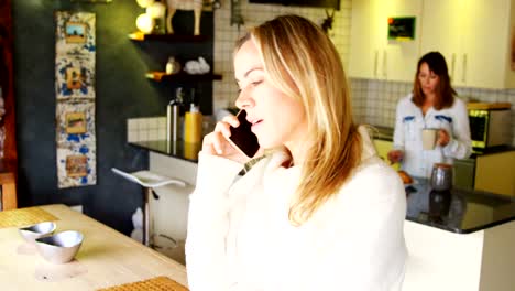 Lesbian-couple-having-coffee-and-talking-on-mobile-phone-4k