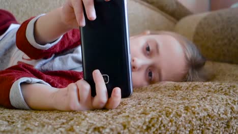 Girl-teenager-watching-a-video-in-the-phone-while-lying-on-the-couch.