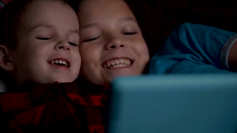 Footage-two-boys-using-tablet-pc-lying-on-sofa.