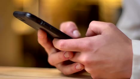 Close-up-image-in-profile-of-female-hands-working-with-smartphone.