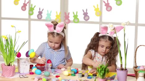 Happy-children-wearing-bunny-ears-painting-eggs-on-Easter-day.