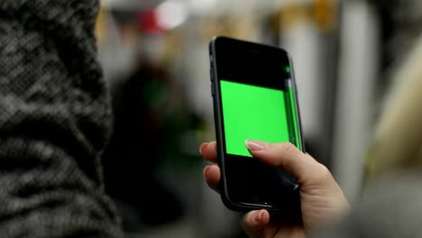 Close-up-view-of-woman-hand-holding-a-smartphone,-sitting-in-public-transport.-Girl-surf-the-Internet-with-touchscreen.