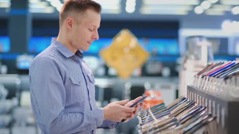 Hombre-probando-nuevo-teléfono-inteligente.-El-interior-de-la-tienda-Tech