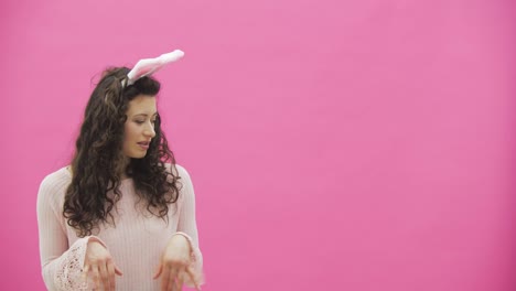 Young-beautiful-girl-standing-on-a-pink-background.-The-girl-moves-like-a-rabbit.-Gently-looking-at-the-camera,-smiling.