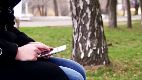 Junge-Frau-mit-Smartphone-auf-einer-Bank-im-Stadtpark