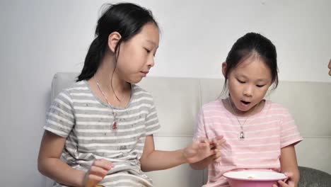 Glückliches-asiatisches-Mädchen-essen-Chips-mit-der-Familie-und-sprechen-zusammen-zu-Hause-in-der-Nacht.