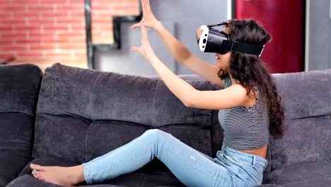 Barfuß-lächelnde-junge-Frau-spielt-Spiel-in-Virtual-Reality-Simulator-Brille-auf-Couch