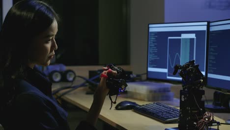 Jóvenes-ingenieros-de-desarrollo-de-electrónica-probando-tecnología-robótica-innovadora-en-laboratorio.-La-joven-hembra-asiática-crea-movimiento-para-la-mano-robótica-mecánica.-Personas-con-concepto-de-tecnología-o-innovación.