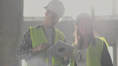 Bauarbeiter-Mann-und-Architekt-Frau-in-einem-Helm,-diskutieren-den-Plan-des-Baus-des-Hauses,-erzählen-einander-über-den-Entwurf,-halten-eine-Tablette,-Blick-auf-die-Zeichnungen,-Hintergrund-der-Sonnenstrahlen