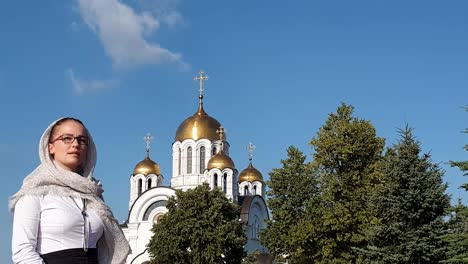 Orthodoxe-Lifestyle-Frau-im-Schal-steht-auf-dem-Hintergrund-der-orthodoxen-Kirche