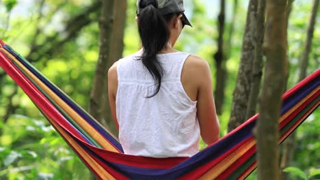 Relaxing-in-hammock-with-smartphone-in-tropical-rainforest