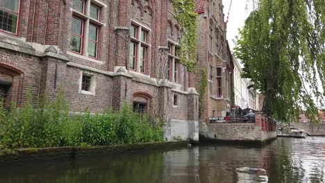 Bruges,-Belgium---May-2019:-View-of-the-water-channel-in-the-city-center.-Tourist-walk-on-the-water-canals-of-the-city.-View-from-a-tourist-boat.