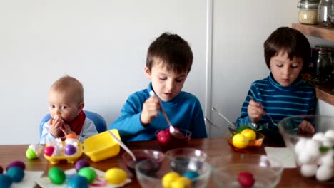 Tres-niños,-colorear-y-pintar-huevos-de-pascua-en-casa-para-las-vacaciones