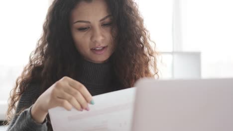 Businesswoman-looking-at-financial-report-and-explaining-data-on-video-call