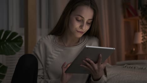 Glücklich-teen-Mädchen-mit-digitalen-Tablet-spät-eabend-im-Schlafzimmer